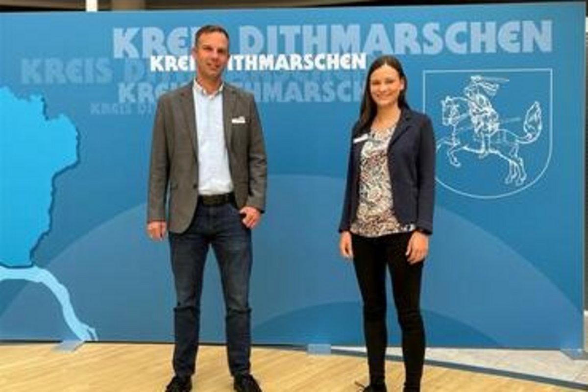 die beschriebenen Personen (links der Mann, rechts die Frau) vor einem Dithmarscher Plakat