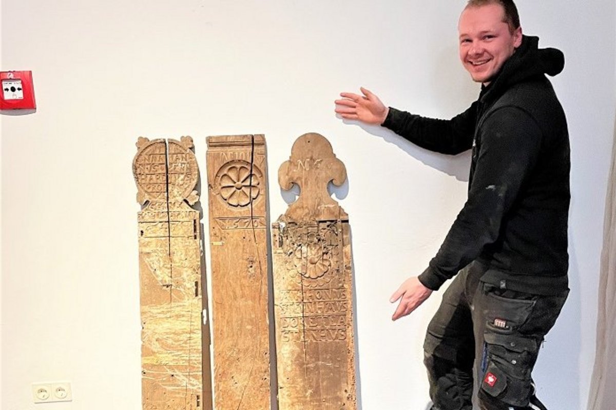 Der Finder Niels Peters und sein Fund: Auf der mittleren und der rechten Wange sind Rosettenschnitzereien. Die Inschrift auf der rechten Wange verweist vermutlich auf die Stifter der Gestühlswangen. Foto: Dithmarscher Landesmuseum