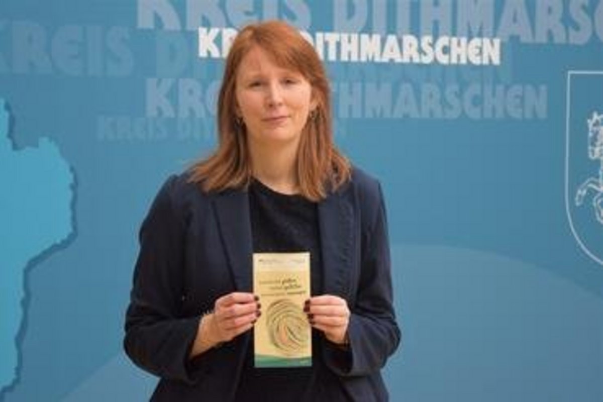 Eine rothaarige Frau mit einem Flyer in der Hand