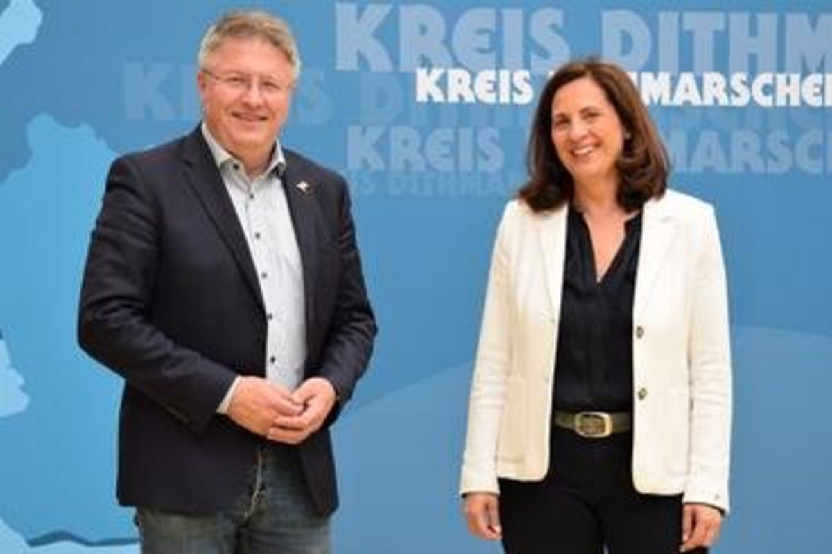 links der Mann, rechts die Frau vor einer Leinwand/Plakat